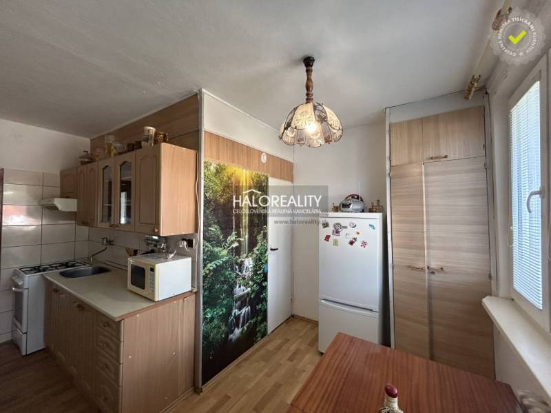 A kitchen unit with a wooden decor and a dining table in a 2-room apartment.