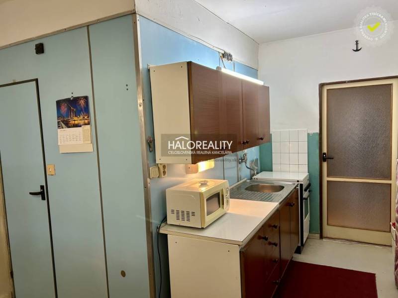 A kitchen with wooden cabinets and white appliances in a 4-room apartment.