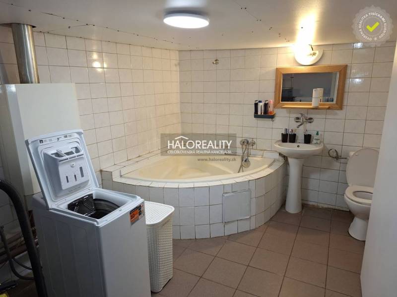 Bathroom in a family house with a bathtub, washing machine, sink, and toilet.
