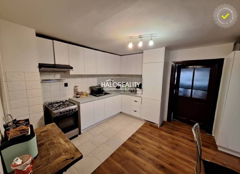 A kitchen in a family house with white cabinets and a wood-patterned floor.