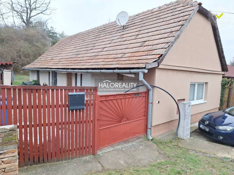 A family house in Brestovany with a tiled roof, a red fence, and a driveway.