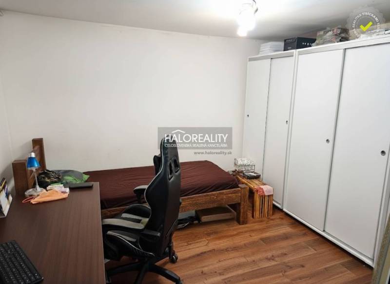 A room with a bed, a desk, a chair, and a floor with a wooden decor in a family house.