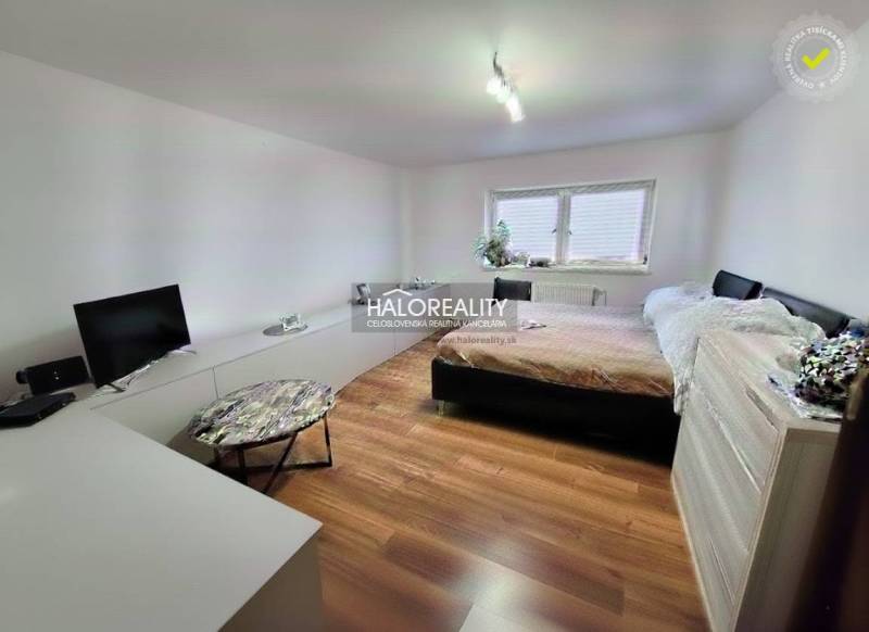 Bedroom with a bed, television, and wooden decor flooring in a family house.