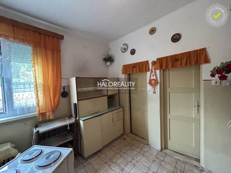 A kitchen in a **family house** with vintage furniture, orange curtains, ceramic decorations.