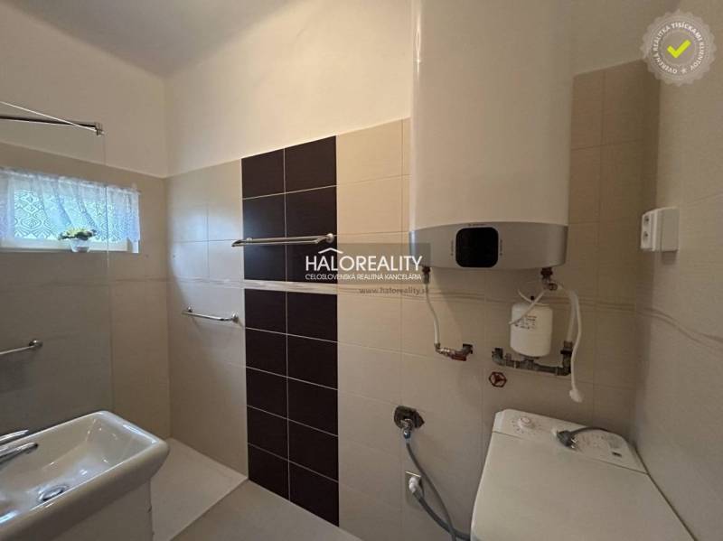 A bathroom in a family house with a sink, faucets, and an electric boiler on the wall.