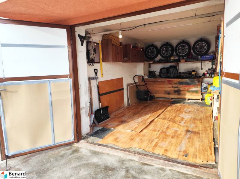 A garage with a wood-patterned floor, storage shelves, and tools.