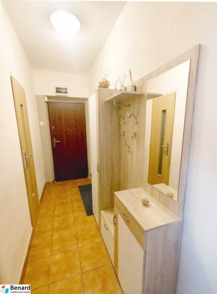 Hallway of a 3-room apartment with tiles and a coat rack with a mirror.