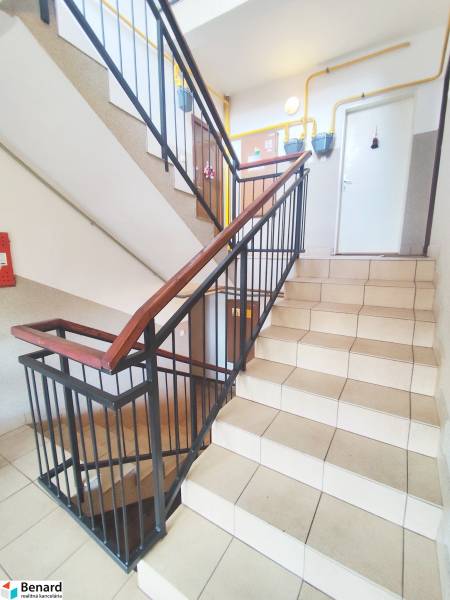 A staircase with tiles and metal railing leading to apartments in the building.