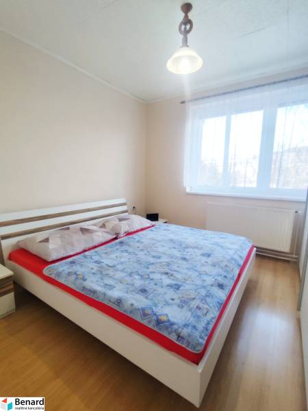 Bedroom in a 3-room apartment with a bed and wooden decor flooring.