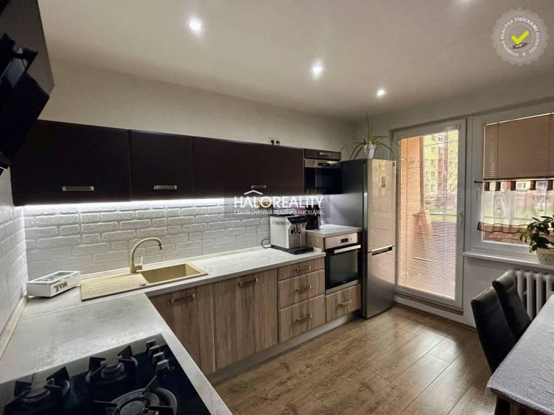 A kitchen with a wooden decor floor in a 3-room apartment, equipped with modern appliances.