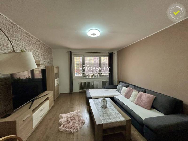 Living room in a three-room apartment with a wooden decor floor and a comfortable sofa chair.