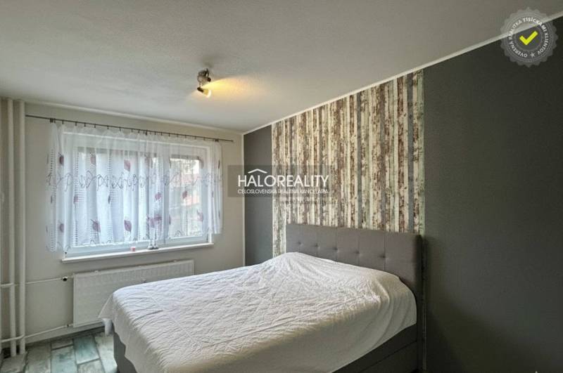 A bedroom with a large bed, wallpaper, and decorative flooring in a 3-room apartment.