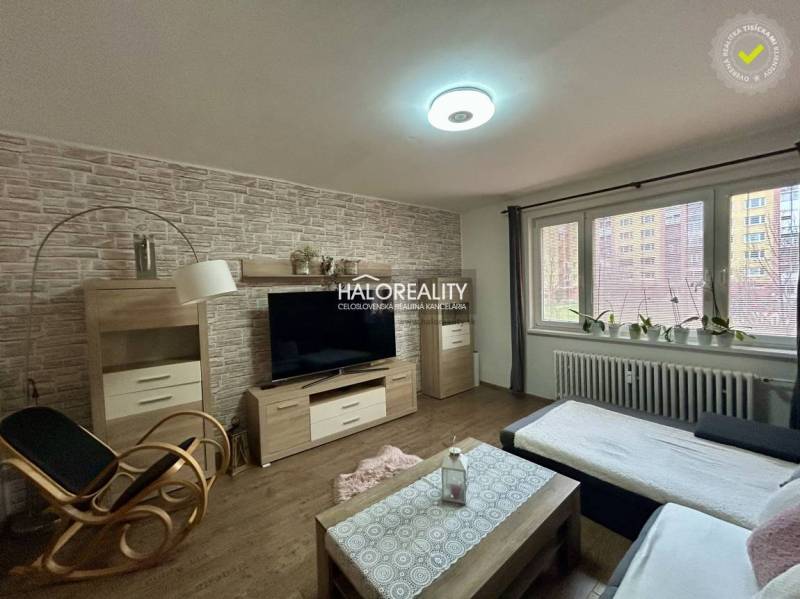 Living room with seating, wood-patterned flooring, television, and decorative wall in a 3-room apartment.