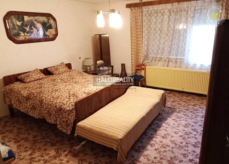 A bedroom with an antique bed, curtains, a painting, and a carpet. The family house offers a cozy space.