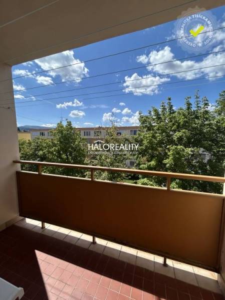 The balcony of a 3-room apartment in Prievidza with a view of trees and the sky.