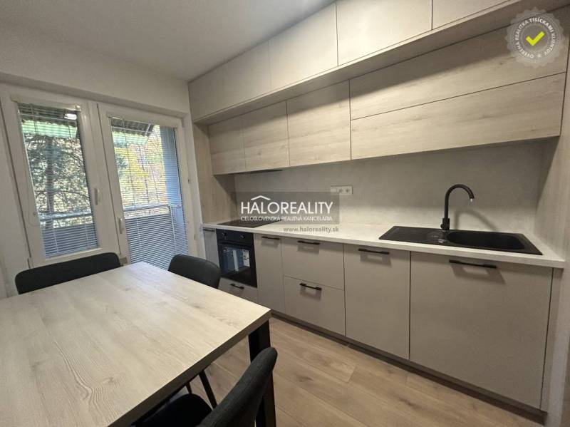 Kitchen in a three-room apartment with a wooden decor floor and a dining table.