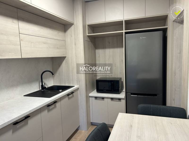 A kitchen in a 3-room apartment with a wooden decor floor, gray cabinets, and appliances.
