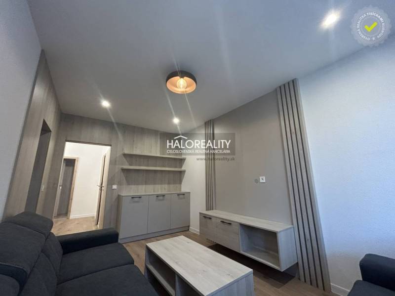 Living room in a three-room apartment with a wooden decor floor and simple furnishings.