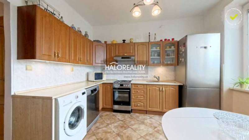 A kitchen with built-in doors, appliances, and a dining table in a two-room apartment.