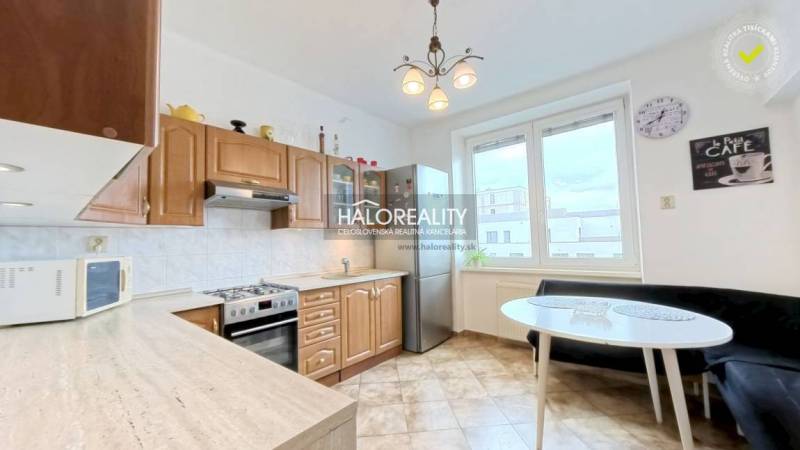 A kitchen in a 2-room apartment with built-in appliances and a dining table.