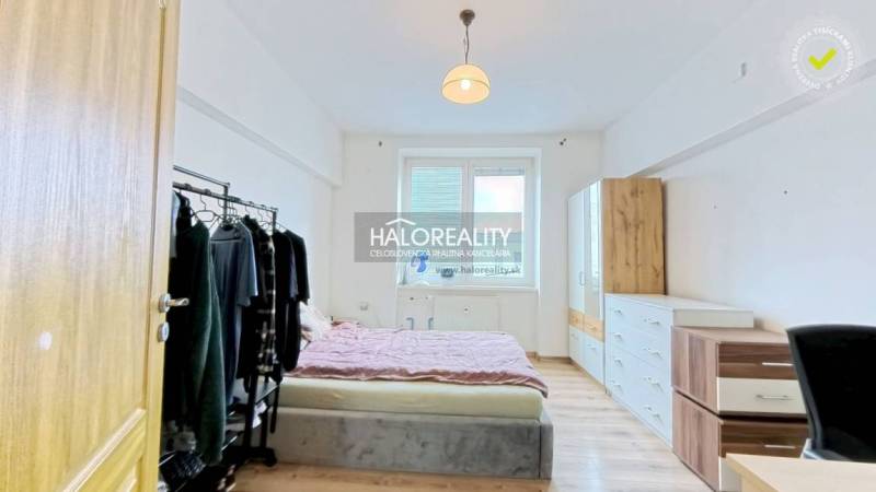 Bedroom with a bed, wardrobe, and dresser in a 2-room apartment with a wooden decor floor.