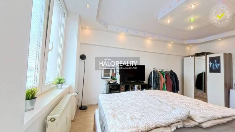 Bedroom in a 2-room apartment with a window and a television, floor with wooden decor.