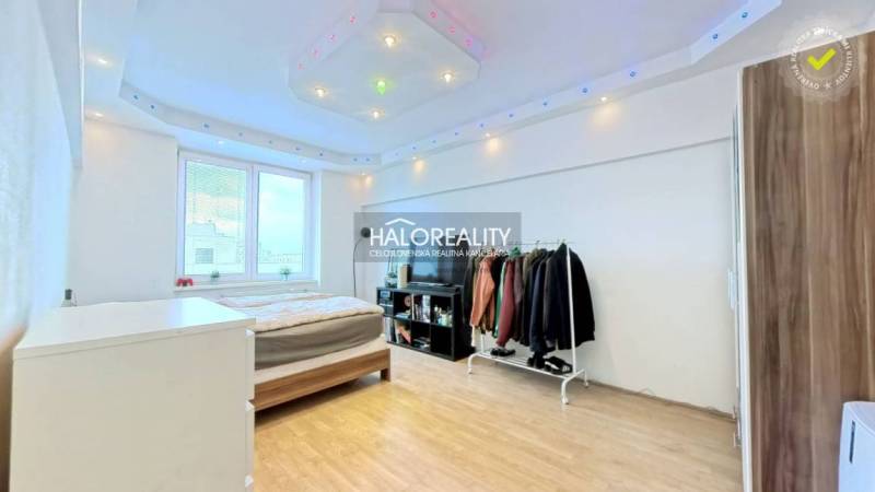 Bedroom in a 2-room apartment with a bed, wardrobe, and wooden decor flooring.