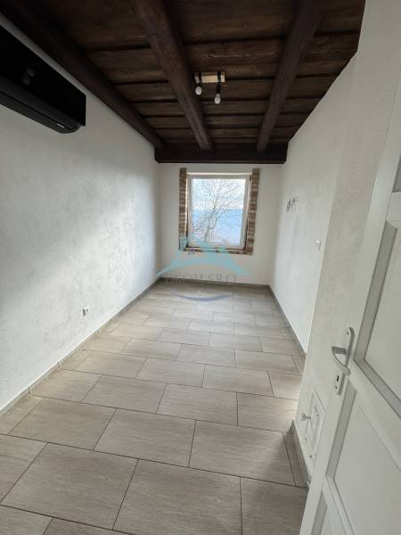 A narrow window in the attic complements the ceiling with wooden beams.