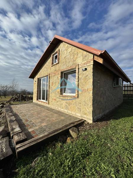 Stone cottage in Šahy with a terrace, surrounded by nature and a blue sky.