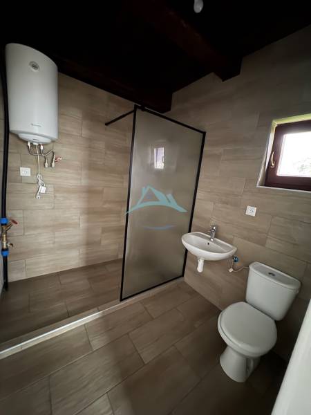 A bathroom in a cabin with a toilet, sink, and water heater, floor with a wooden decor.