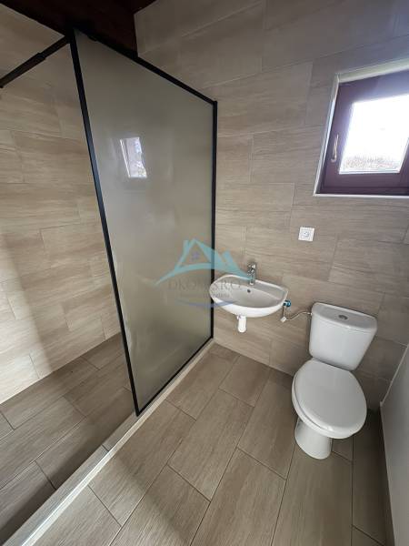 A bathroom in a cabin with a shower, sink, and toilet, floor with wood decor.