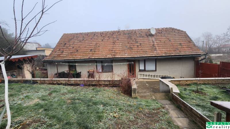 A family house in Brestovany with a traditional roof and a landscaped garden during autumn.