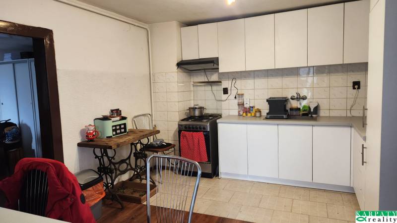 A kitchen with white cabinets and a wood-patterned floor in a family house.