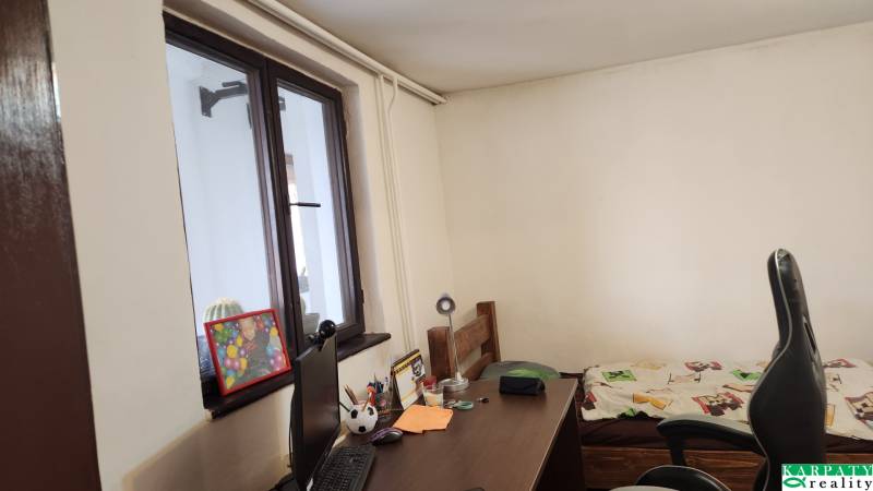 A workspace in a family house with a wooden desk, bed, and decorations.