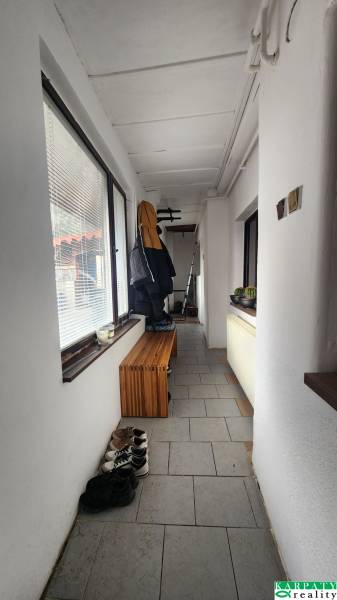 A narrow hallway with tiles, a bench, and a coat rack in a family house.