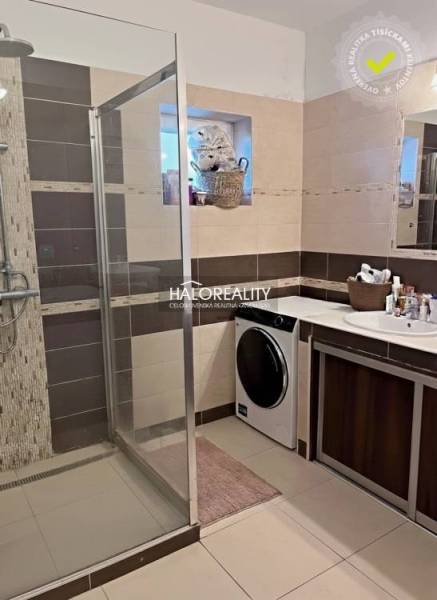 A bathroom with a spacious shower, washing machine, and sink, decorated in brown tones.