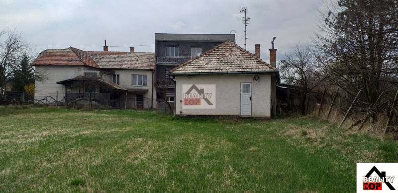 A family house in Studená with a large plot and older buildings in the background.