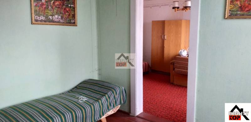 A room in a family house with carpets, older furniture, and a painted picture on the wall.