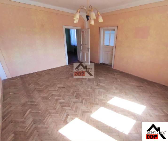 Living room with parquet flooring and a chandelier in a family house, two doors, light orange walls.