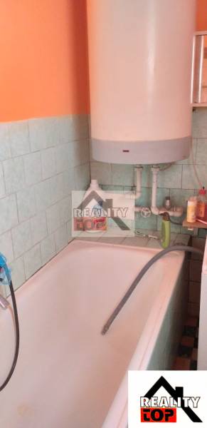 Bathroom with a bathtub, water heater, and tiles.