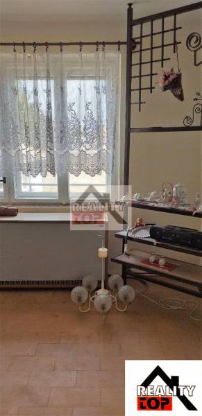 A room in a family house with a shelf, curtains, and decorations.
