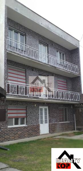 A three-story family house in Studená with balconies and paving stones in the yard.