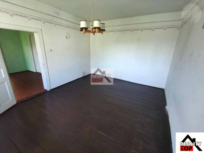 Interior of a family house with a dark wood-patterned floor and a chandelier.