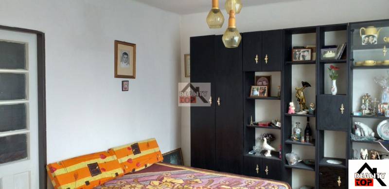 A bedroom in a family house with dark furniture, decorations, and enlarged photographs on the wall.