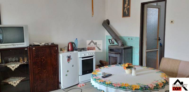 The interior of a family house with a tile stove, a television, and a dining table.
