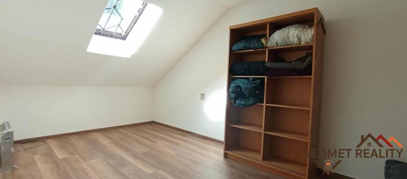 Attic room in a cottage with a shelf and a wooden decor floor.