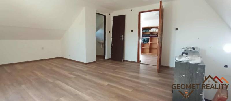 The attic of the cottage with a wooden decor floor and built-in cabinets.
