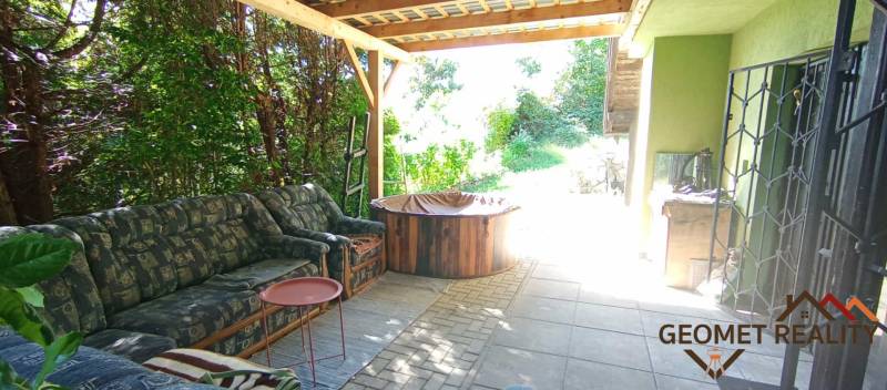 Covered terrace of the cottage in Ružiná with a seating set and surrounding greenery.