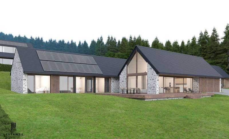 Stone house in Tajov with photovoltaic panels on the roof, surrounded by forest. Development plots.