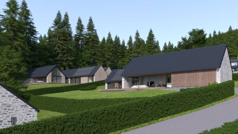 Development plots in Tajov with modern family houses and a forest backdrop.